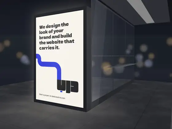 A backlit poster in a bus shelter at night
